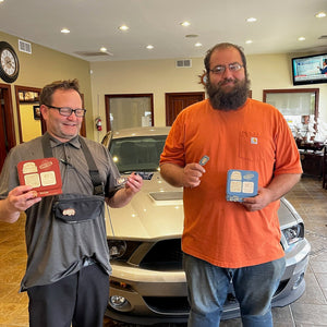 Two people holding tapkeychains products for their dealership testimonial