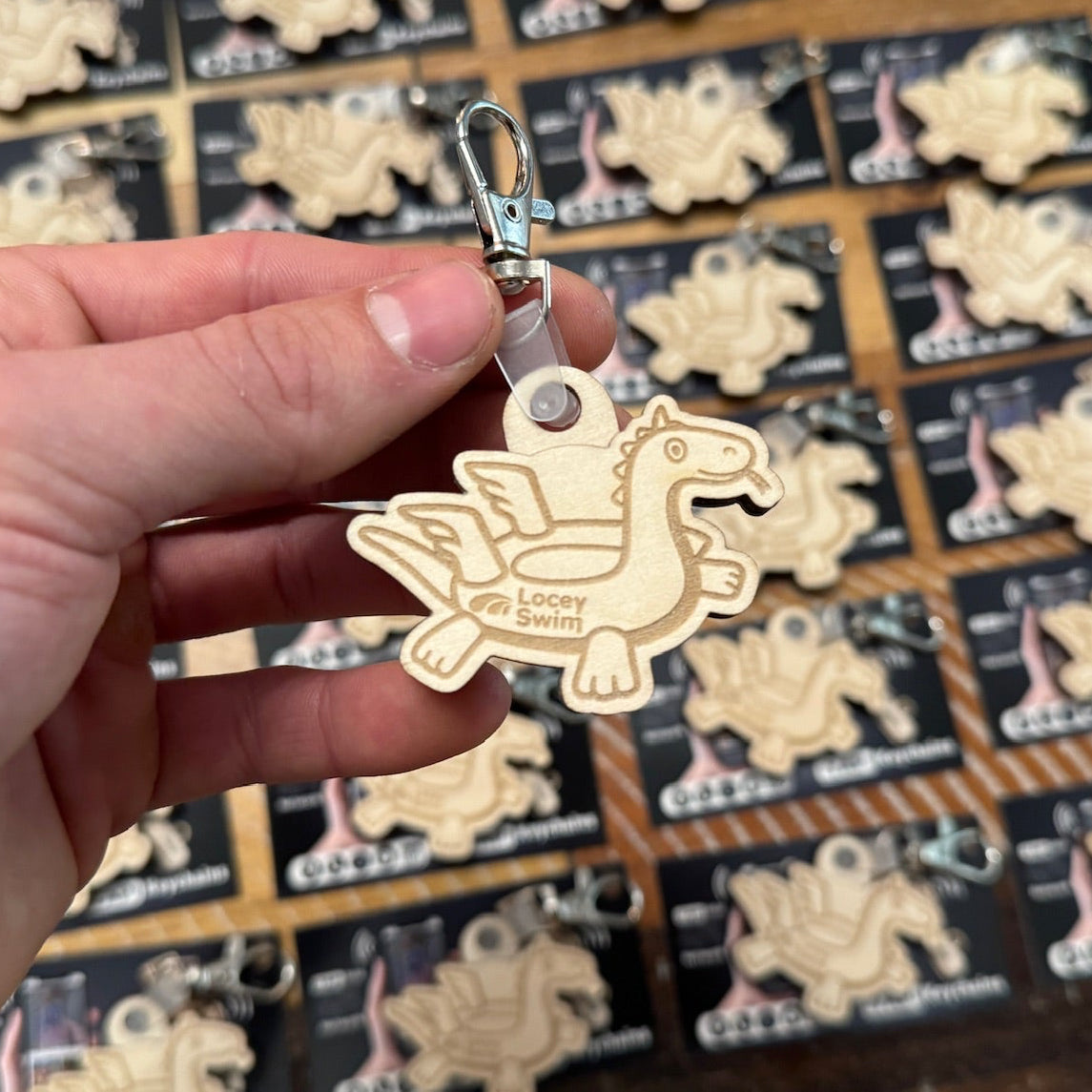 Hand holding a wooden dragon NFC keychain Bulk for event
